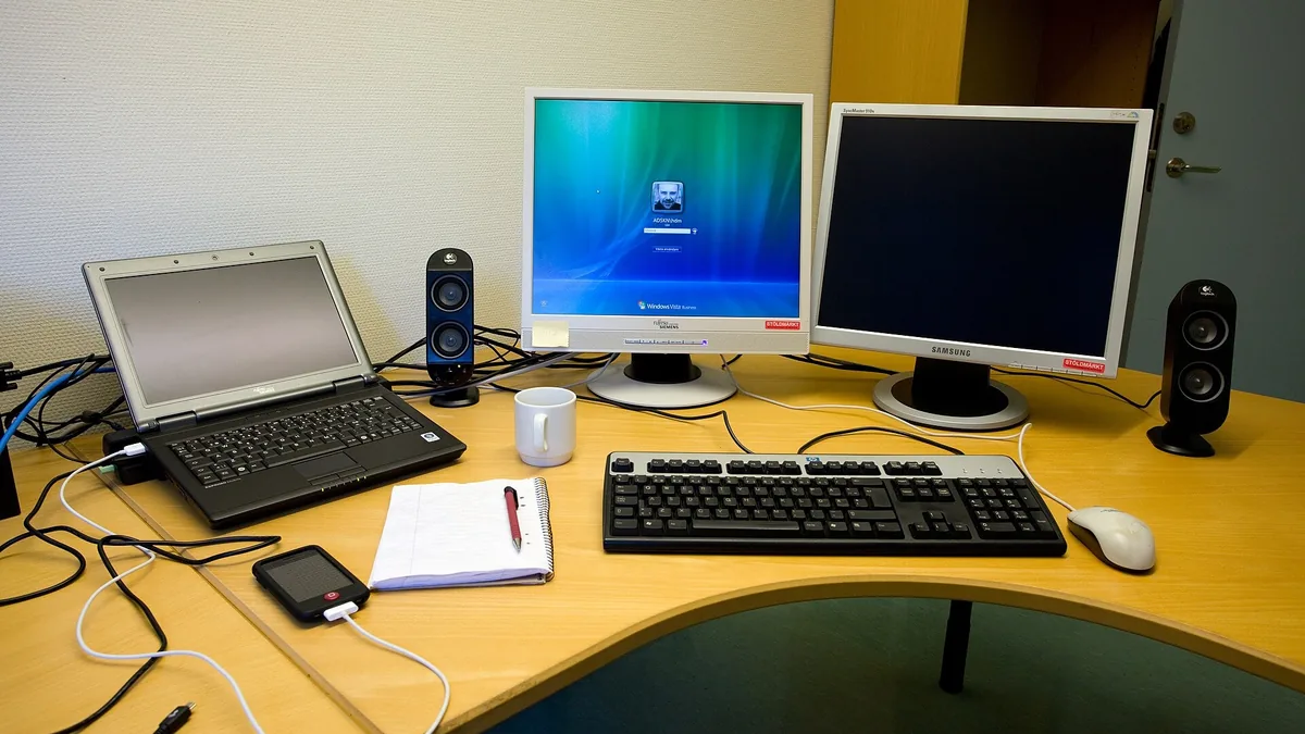 A desk with a laptop, a monitor and a keyboard set up for working at home