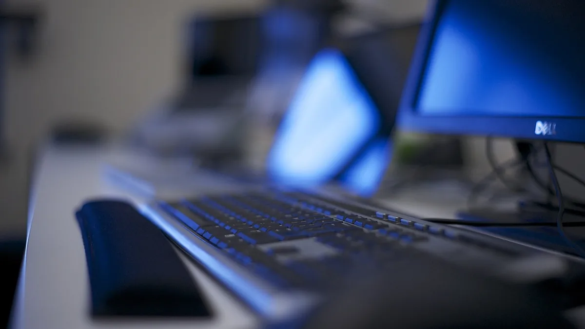 Close-up of a keyboard in front of two computer monitors
